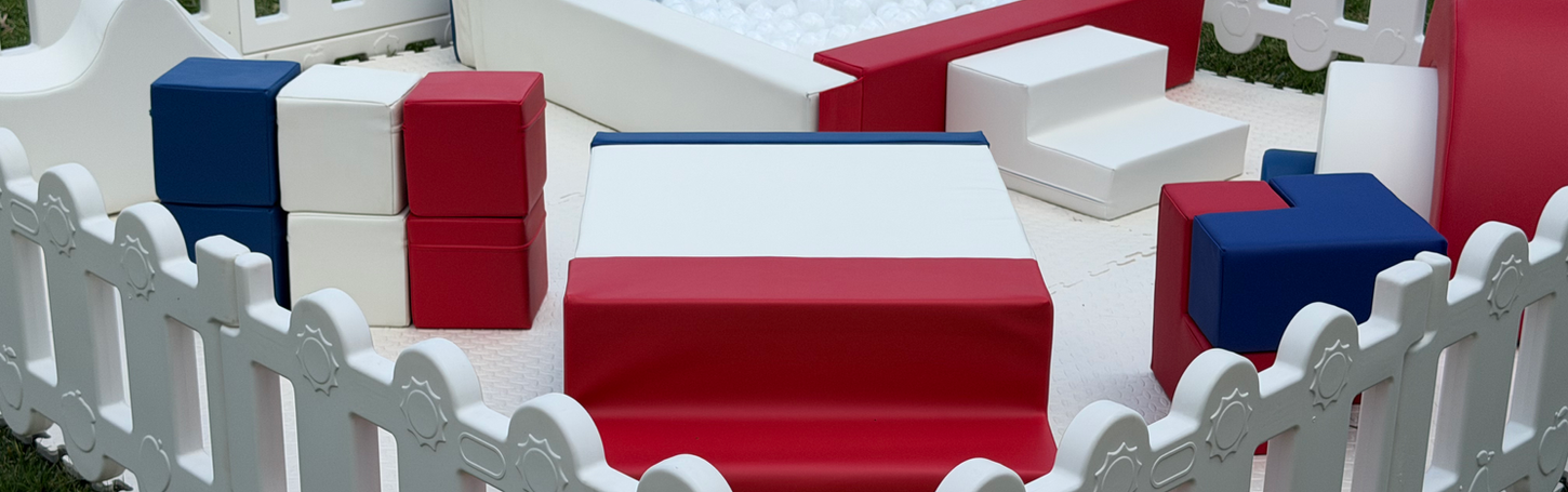 Red, white, and blue soft play set for kids in a fence.