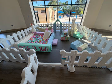 Pastel colored soft play rental with grey floors, white gates and a pastel themed ball pit