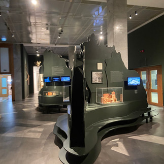 A museum setting with a black curved structure in the middle