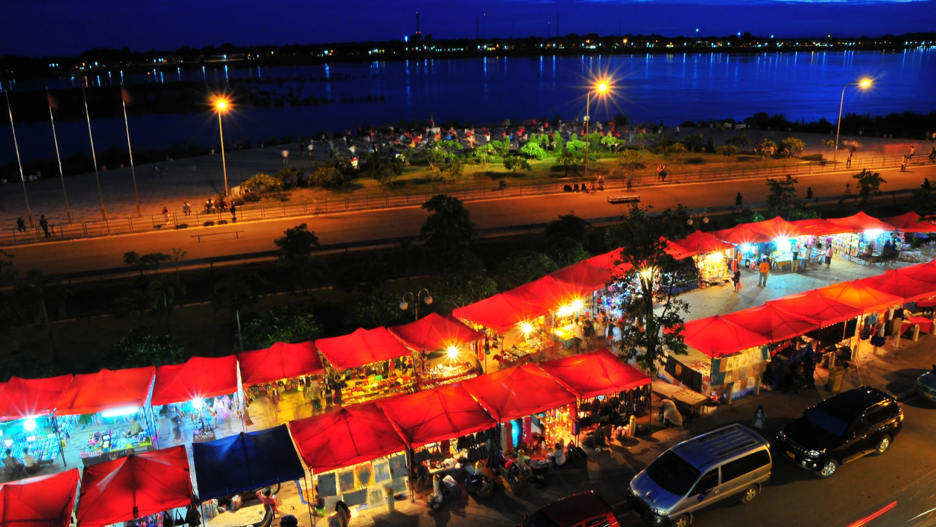 Red tents in a row, photo taken from above and the ocean is in the background, setting is taken at night