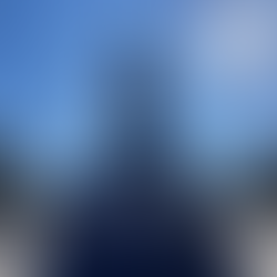 Statue with a flag pole either side. Blue sky with sun in the top right