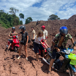 A group of travellers completing the Thakhek Loop, stuck in some deep mud