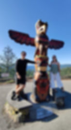 A couple standing next to a Totem pole on Vancouver island
