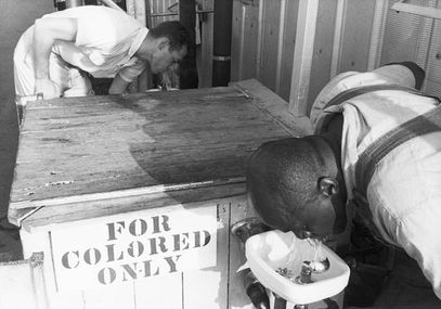 Two men drink from segregated water fountains.