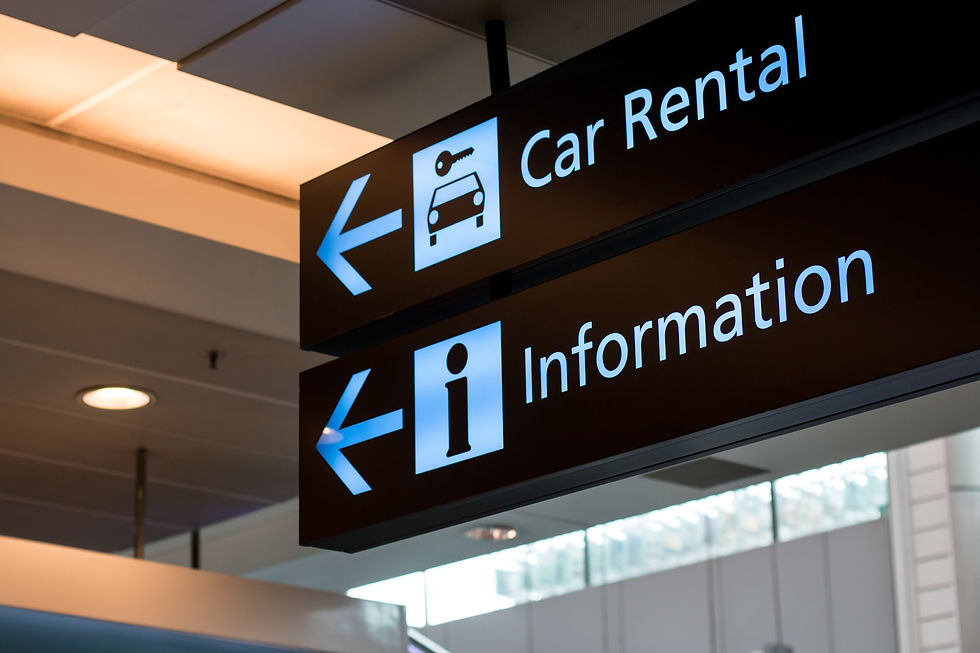 Overhead airport sign showing directions to "Car Rental" and "Information" areas with arrows pointing left.