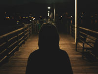 Person standing alone on a pier at night, symbolizing how thought patterns and attention shape mindset, emotional resilience, and self-leadership.