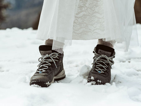 Wedding dress with hiking boots in the snow for winter elopement vibes.
