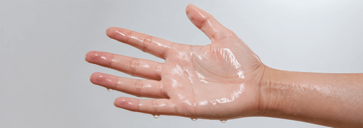 A wet hand with droplets on the palm and fingers, open against a light gray background, suggesting freshness or cleansing.