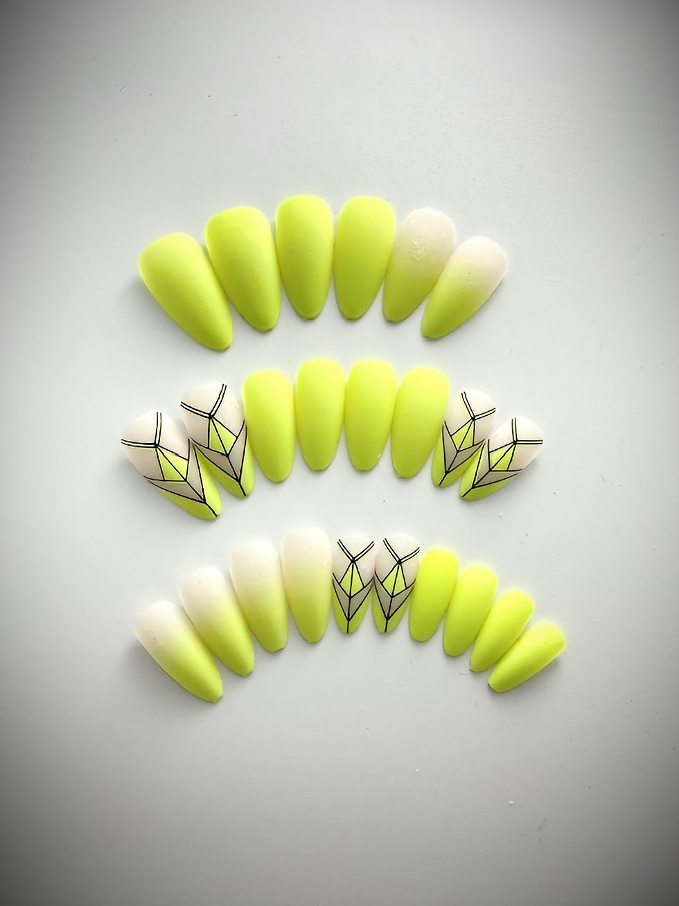 The Genesis set features an intricate black and yellow design, as well a cream base with a yellow ombre accent nail design