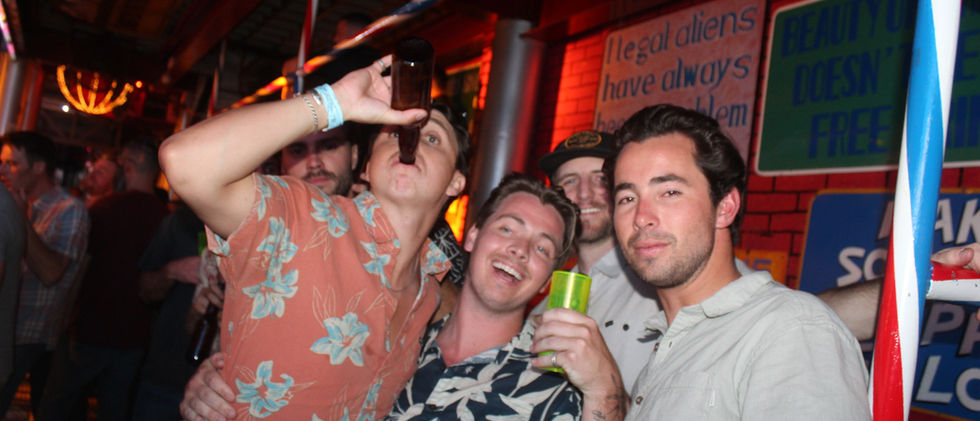 Four men at a bar, smiling for a photo