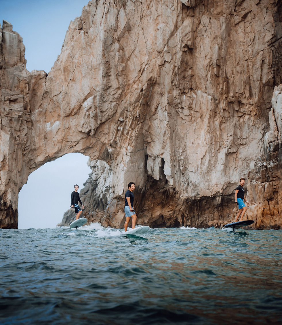Three people doing electric surf in Cabo, Mexico in front of the Arch.