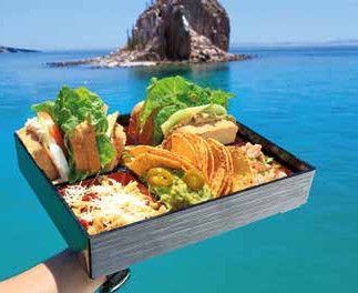 Hand holding out a tray with sandwiches and tacos. 
