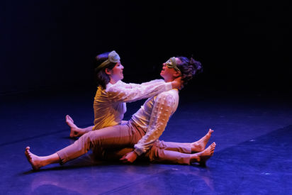 Shira Yaziv with a green monster mask covering her eyes, sitting in Megan Lowe's lap.