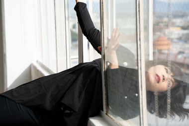 Megan Lowe is dancing with the top half of her body hanging out a window.