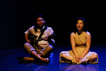 Megan Lowe and Josh Icban with his guitar, sitting and singing.