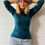 Thumbnail: Woman wearing the teal marl Monroe cowl neck merino top in a relaxed lifestyle pose.