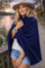 Woman wearing the midnight blue Merino Travel Wrap in a relaxed summer lifestyle pose.