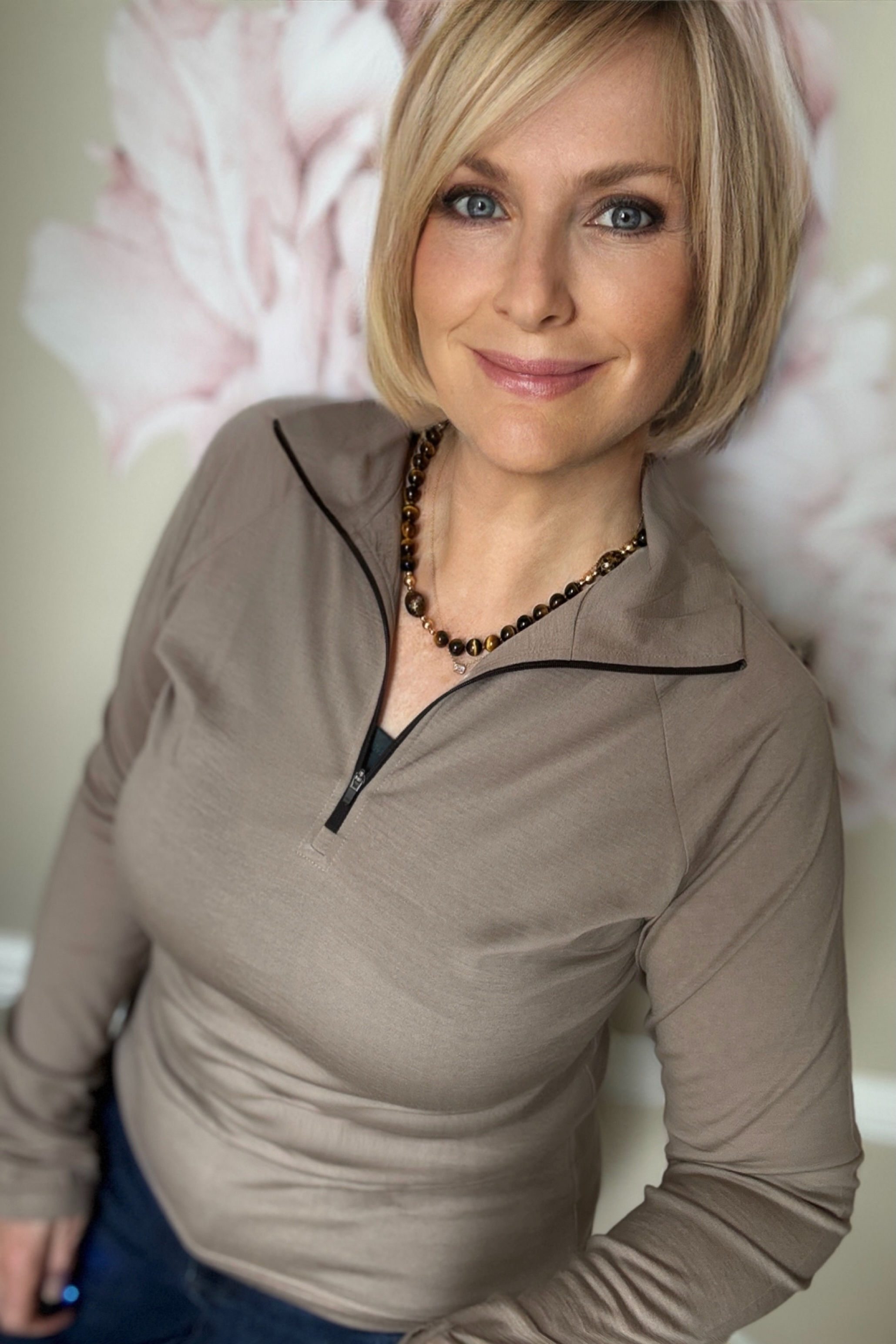 Model wearing the women’s Riley zip-neck top in burlywood lightweight merino jersey, full-body lifestyle pose.