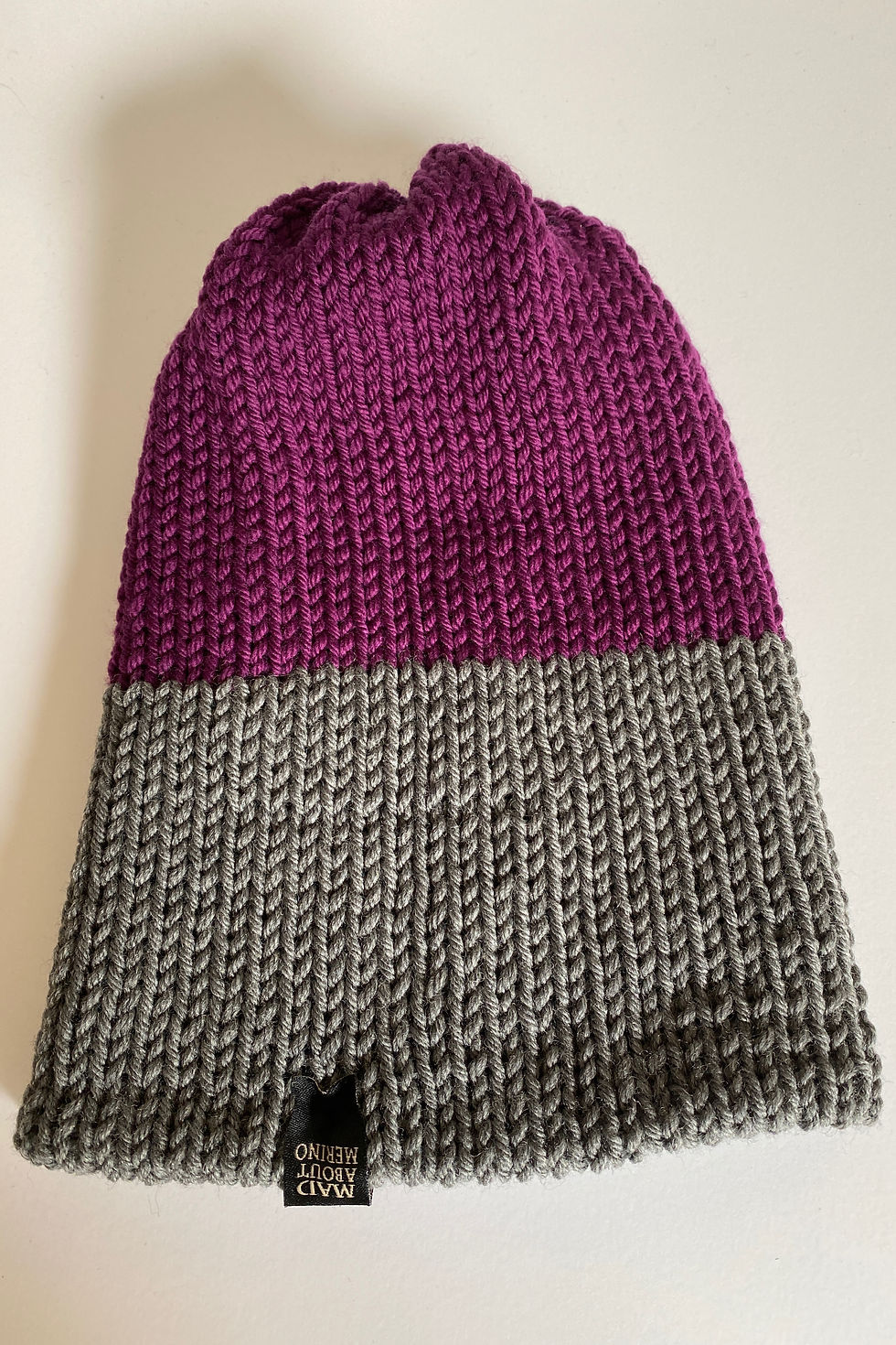 Thumbnail: Close-up of reversible merino beanie in berry, heather grey, and red showing knit texture.
