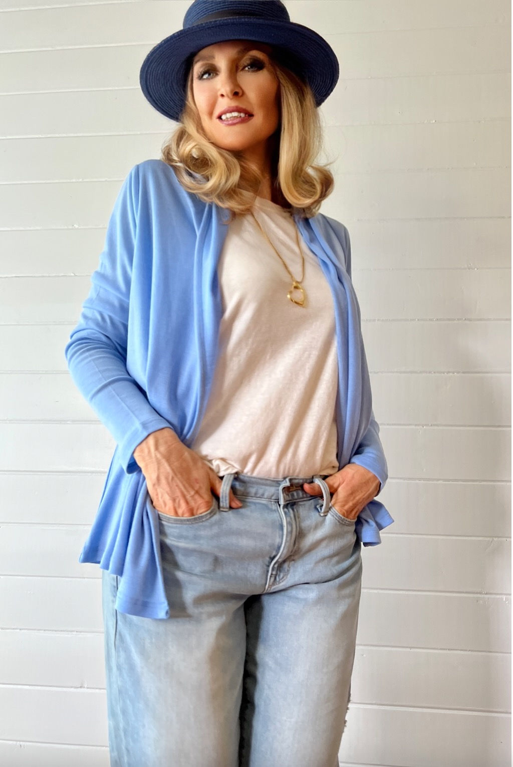 Model wearing the Jesse cardigan in sky blue mid-weight rib merino wool, full-body lifestyle pose.