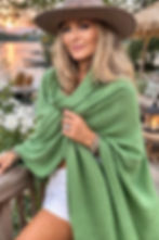 Model styling the apple green Merino Travel Wrap in a draped outdoor pose, showing versatility.”