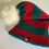 Thumbnail: ELF Pom Beanie in red and green with white pom shown from an angled product view.