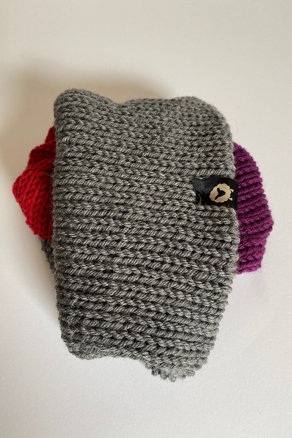 Thumbnail: Reversible merino beanie in berry, heather grey, and red folded to show color blocking.