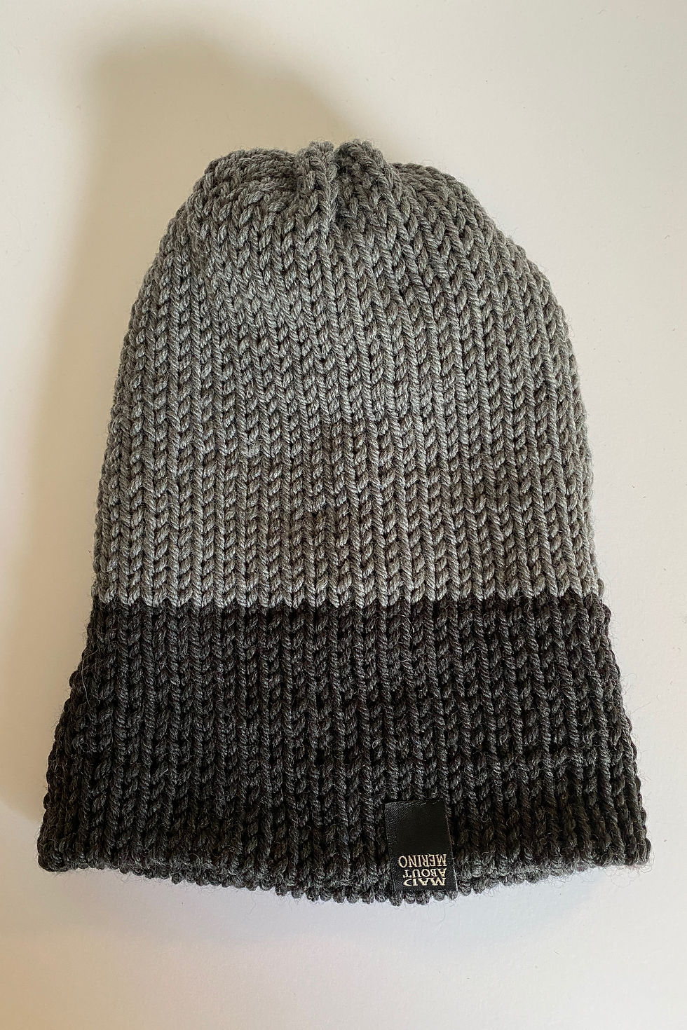 Thumbnail: Close-up of the reversible merino beanie in charcoal, and heather grey showing knit texture and stitching details.”