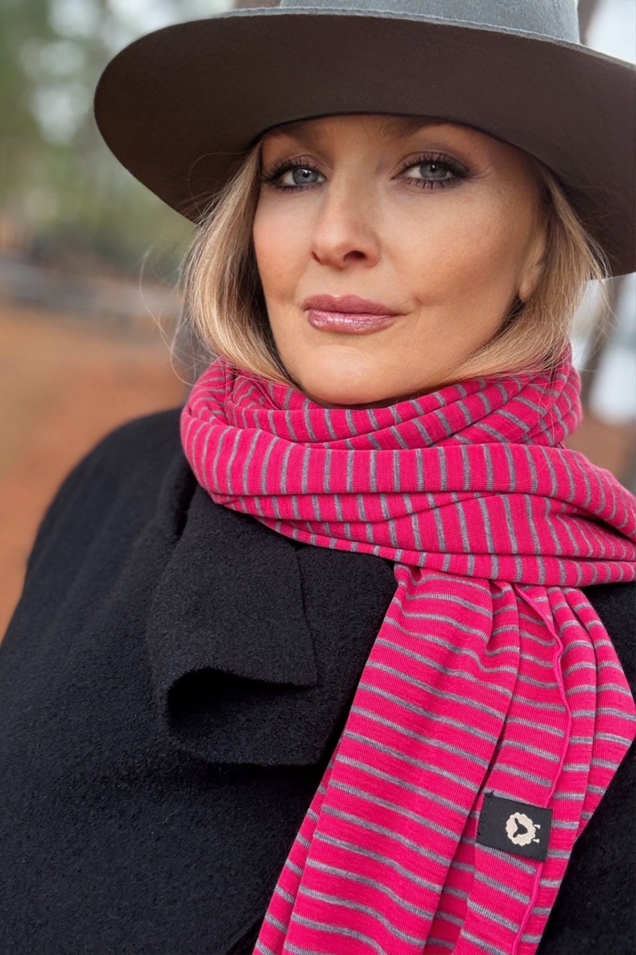 Model wearing the Merino Travel Wrap and Scarf in rose stripe mid-weight rib merino wool, full-body lifestyle pose.