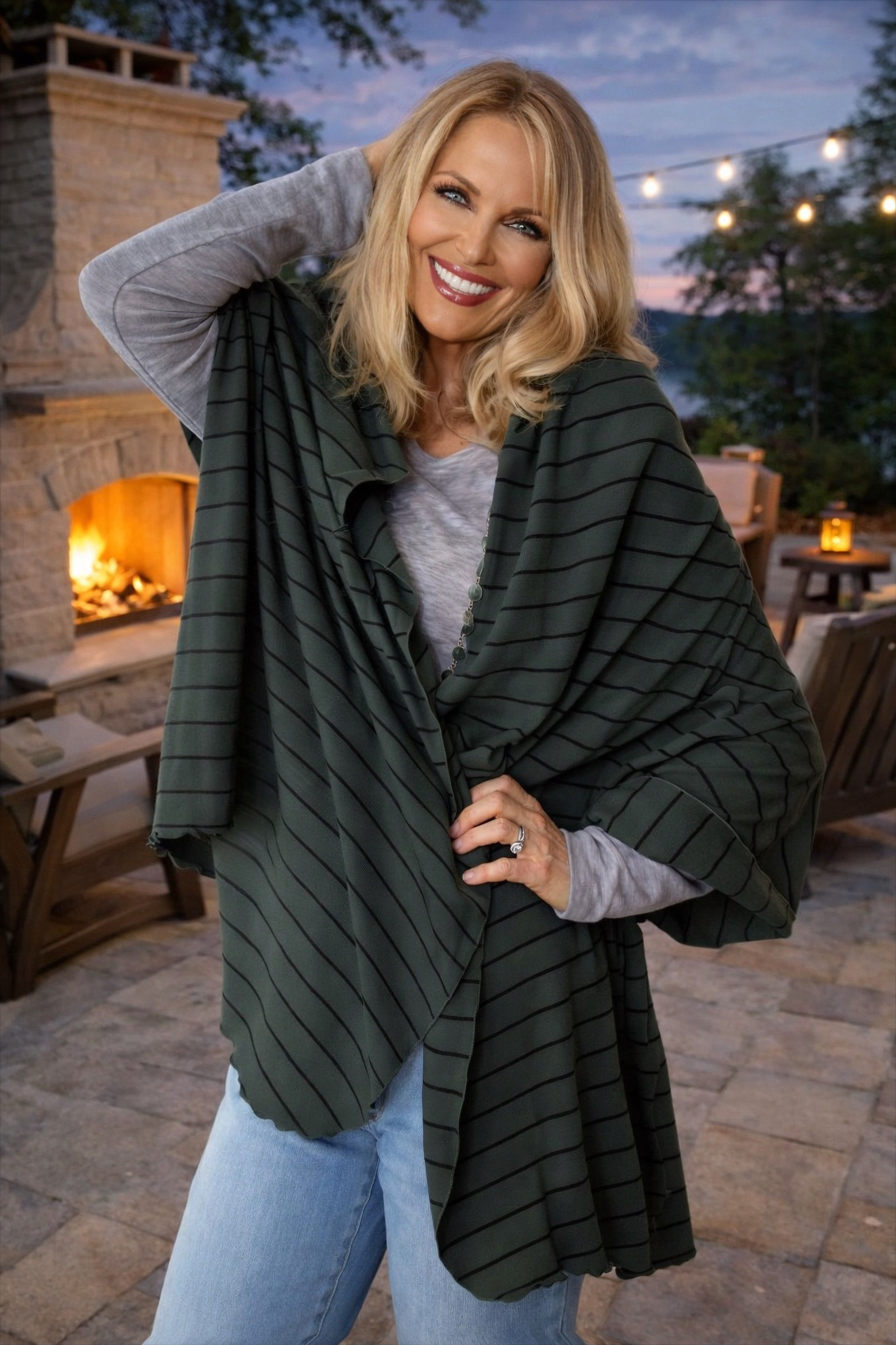 Model styling the olive striped Merino Travel Wrap and Scarf in a draped outdoor pose, showing versatility.