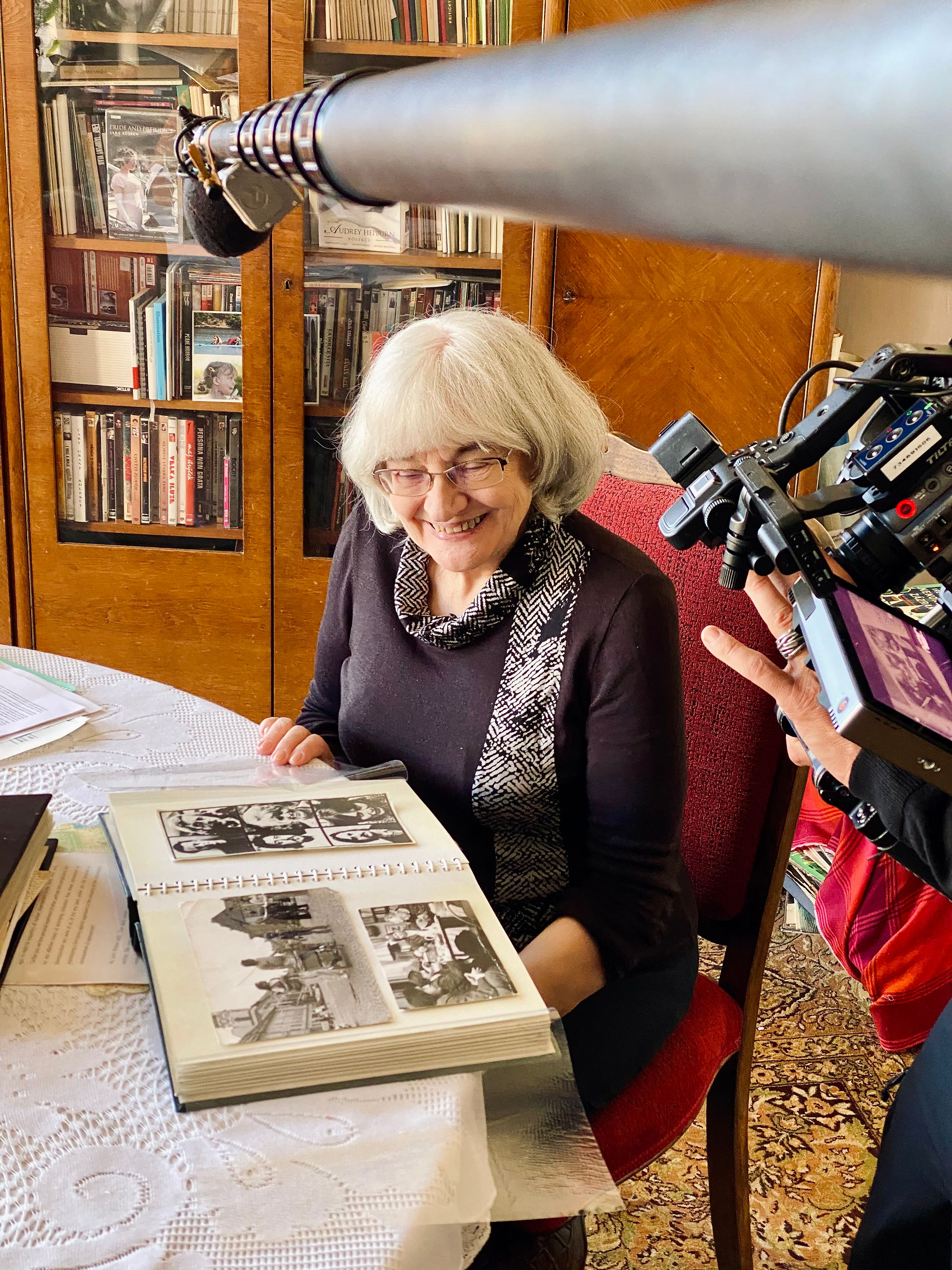Elderly woman reviewing old photos during filming