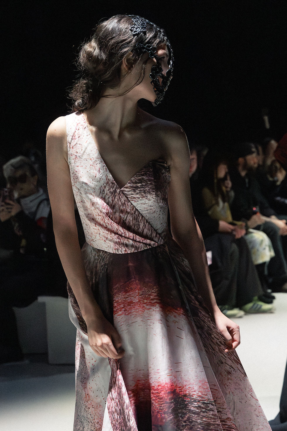 Model walks the runway at Berlin Fashion Week FW26 wearing a Rebekka Ruétz asymmetrical dress with abstract red-toned print and sculptural detailing, photographed by Mariia Dred.