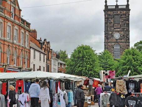 View of Burton-upon-Trent high street with local market stalls and historic church tower.