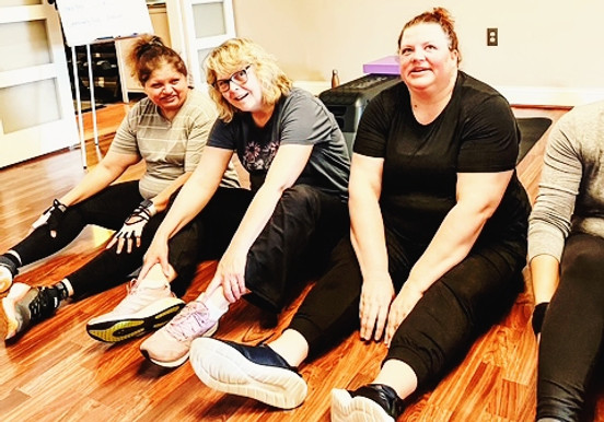 Four women stretching on hardwood floor