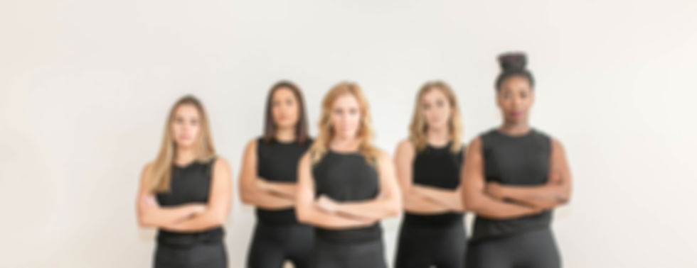 Five women in black tank tops, arms crossed, confident