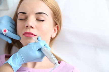 Woman getting her lips tattooed with color.