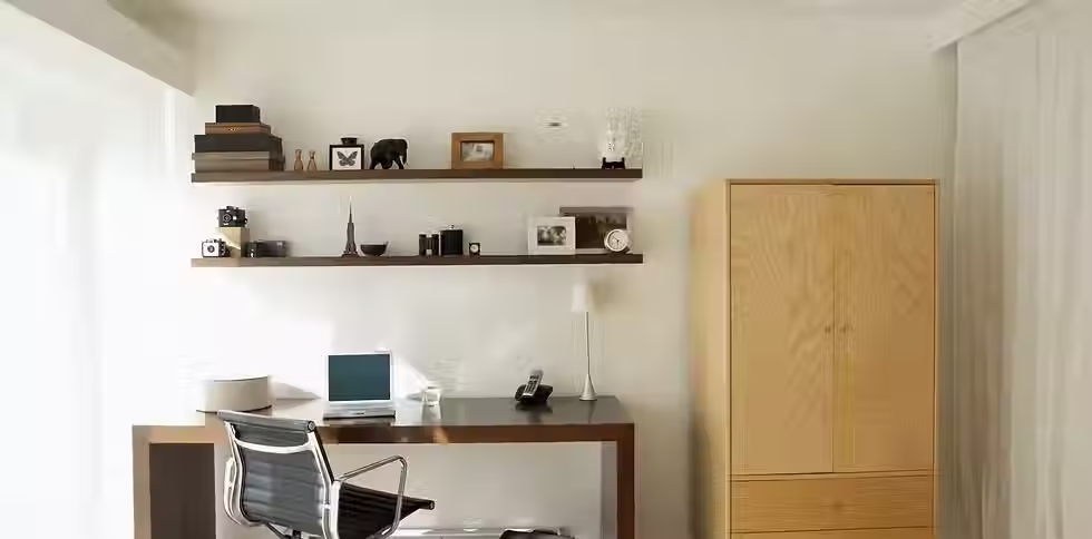 Bespoke home office study area with floating shelves, dark desk, and natural wood cabinet