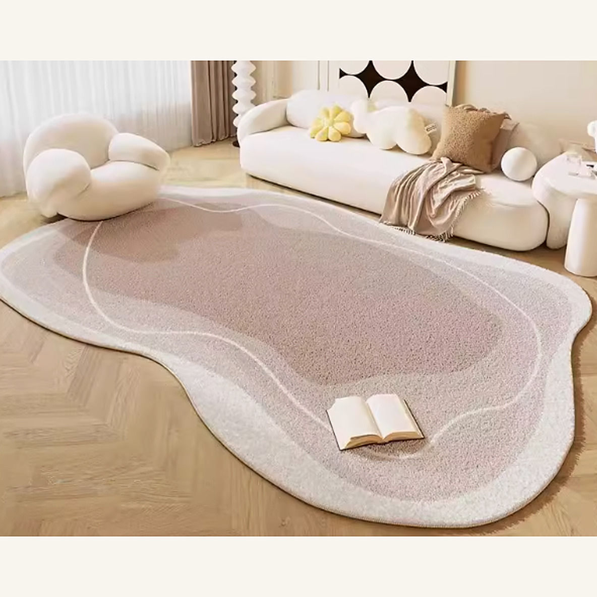 Irregular-shaped rug with a rosy-taupe center and cream border on a light herringbone floor in front of a cream sofa