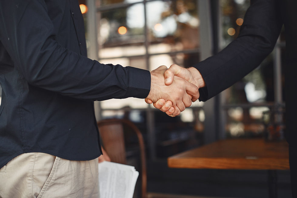 two individuals shake hands wearing professional business attire during negotiation.