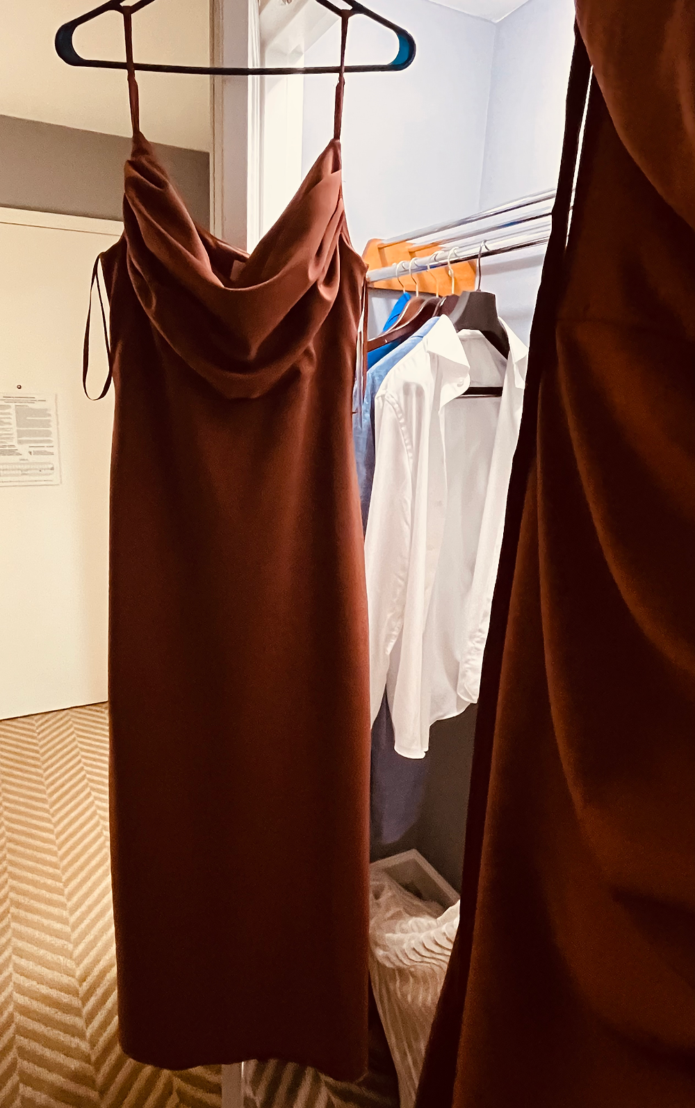 Elegant brown cowl neck dress hanging neatly on a hanger, suggesting a professional clothing steaming service