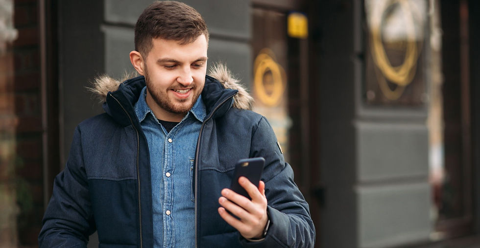 Mosolygós férfi okostelefont néz egy Tinder fotózáson.