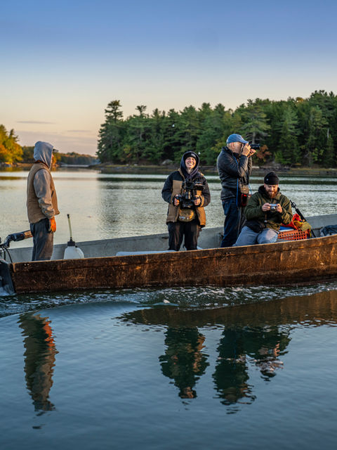 Izzy and the UMaine video crew are being transported via boat to harvest oysters. Izzy is smiling hard.