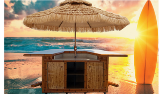 Bamboo tiki bar with thatch umbrella on a beach at sunset alongside surfboard standing in the sand