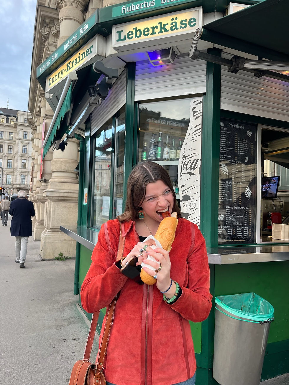 Taking a bite of a Käsekrainer while walking through the city