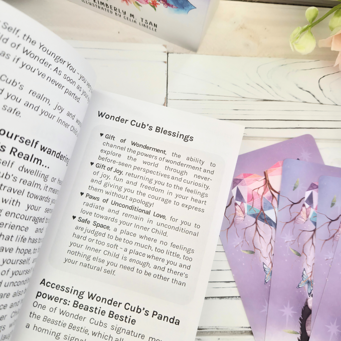 Thumbnail: Inside pages of the League of Pandas Pawbook guidebook open to Wonder Cub's Blessings, with holographic card backs visible be