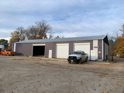 Roads shop, gravel parking lot, blue skies, clouds white truck, orange car