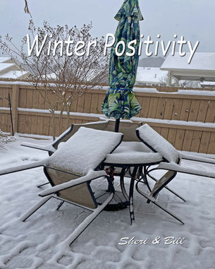 image of round patio table with colorful umbrella bungeed in the middle and chairs tipped onto the table with 3 inches of snow covering chairs and table. Text says Winter Positivity (original photography by Sheri & Bill)