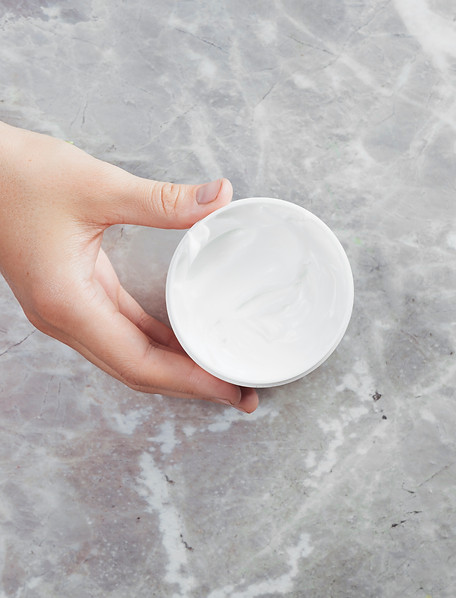 hand-holding-cream-container-marble-background.jpg