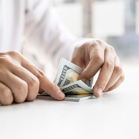 A businessman counting his dollar bills on a white table