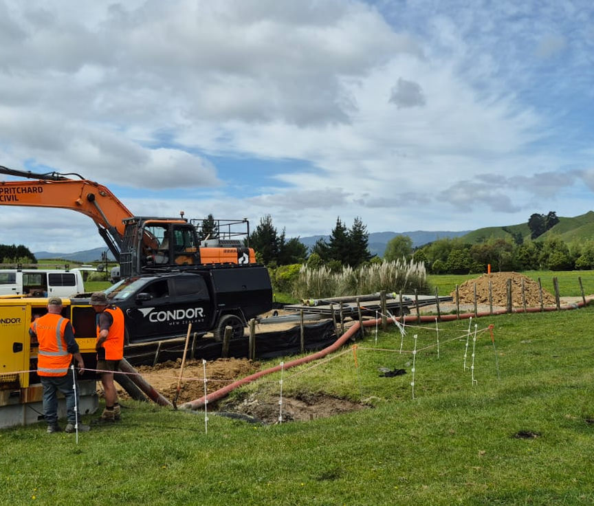 2 men talking infront of a Condor pump and ute, as well as in front of Pritchard Civil's digger
